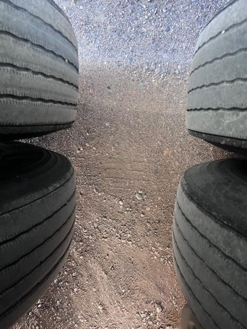 Rear view of a 2022 Utility 3000R trailer tires and gravel ground between dual tires.