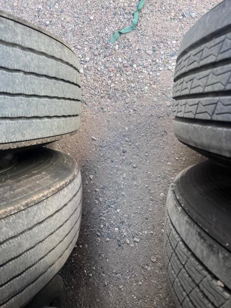 Trailer tires stacked with gravel ground between, side-by-side view