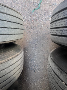 Trailer tires stacked with gravel ground between, side-by-side view