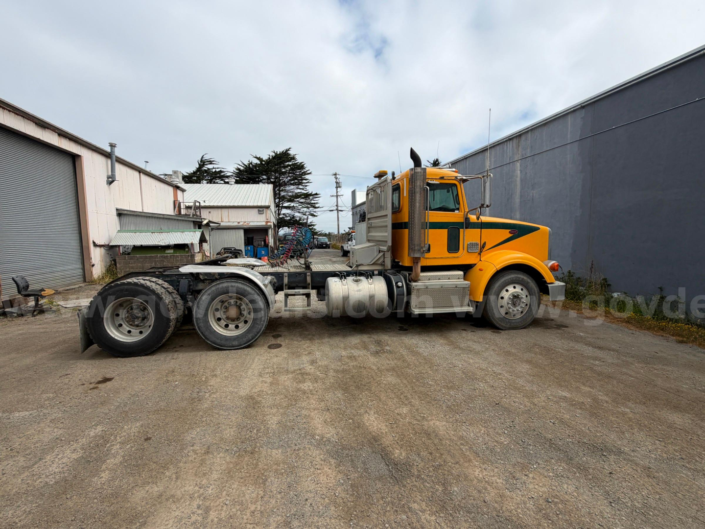 Peterbilt 367 sleeper cab tractor in yellow and gray, side view showing fifth wheel and rear axles.