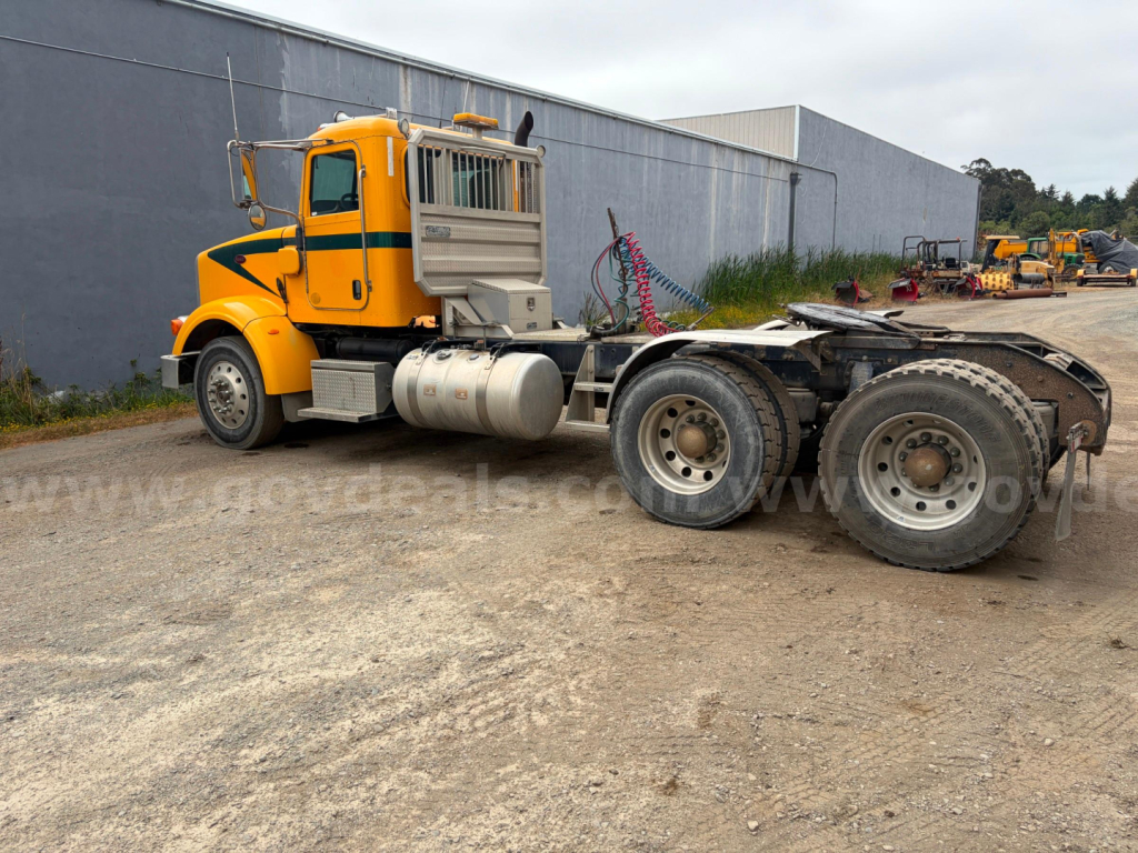 Yellow Peterbilt 367 truck tractor in a lot, side view showing cab, fuel tanks, and rear wheels; no visible text legibly on the image.
