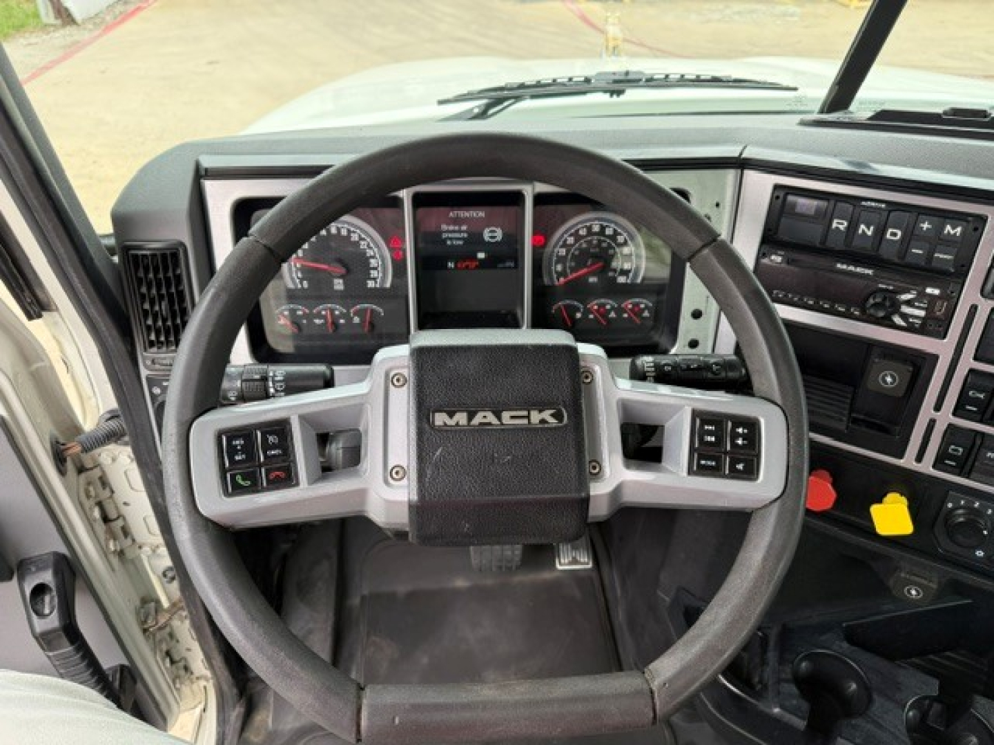 Mack PI64T truck interior showing steering wheel, dashboard gauges, and control panel.