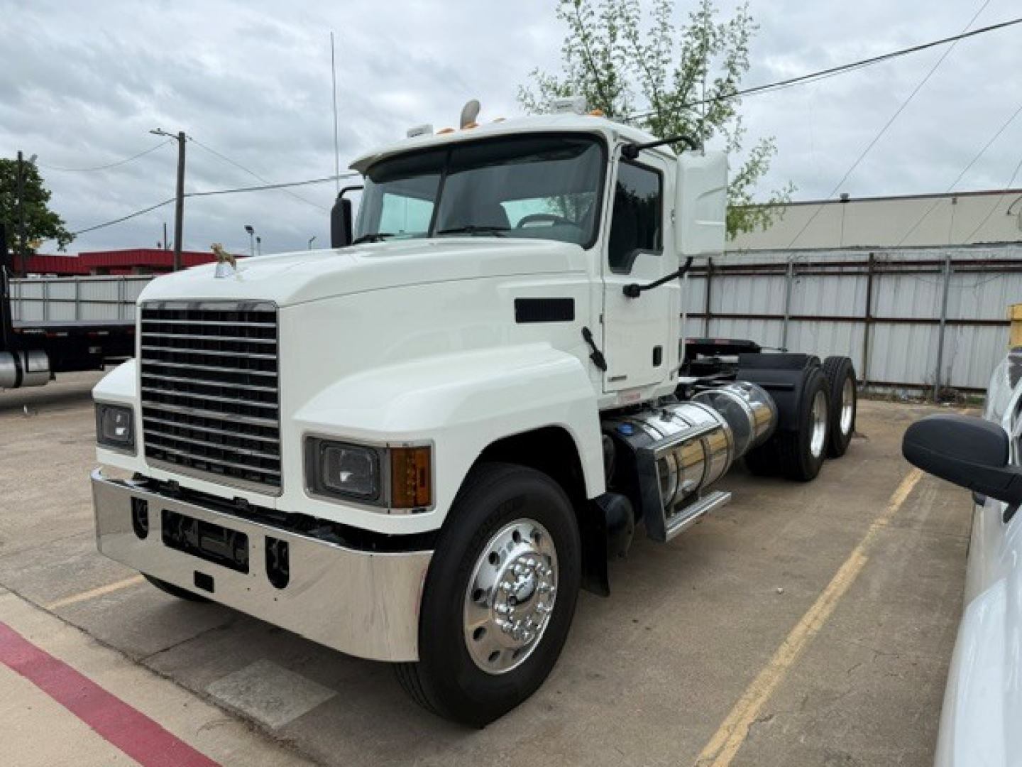 Mack PI64T conventional daycab tractor in white showing front grille, headlights, fuel tanks, and side steps.