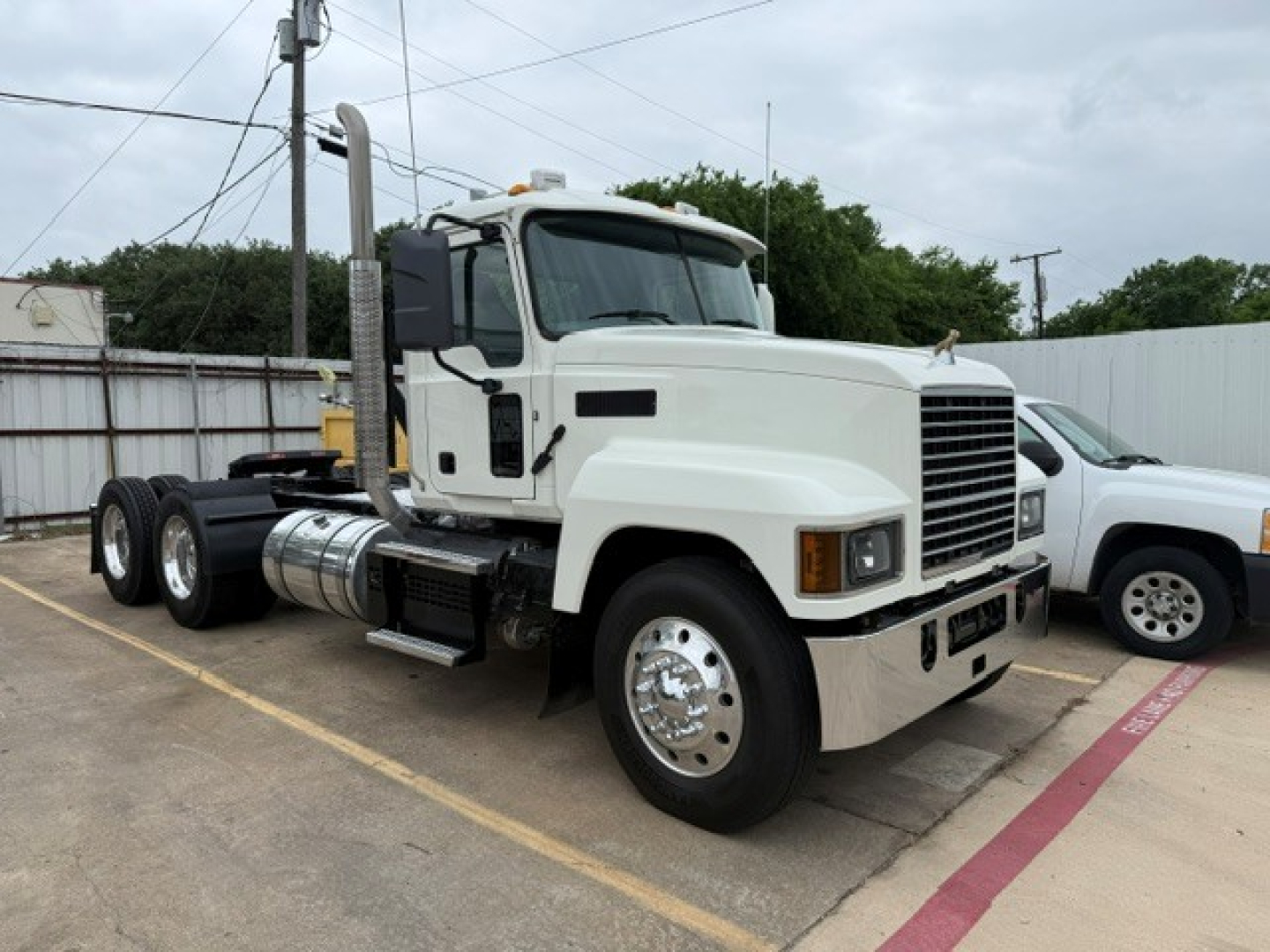 Truck cab and chassis showing Mack PI64T with white exterior and tall exhaust stacks.