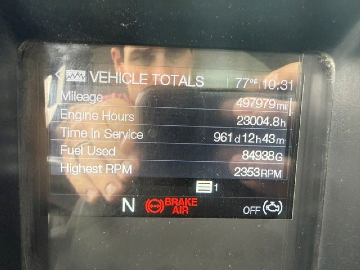 Vehicle totals display on Mack PI64T cab dash showing mileage 497,979 mi, engine hours 23,004.8 h, time in service 961d12h43m, fuel used 84,938 gal, highest RPM 2,353 RPM, N brake status.