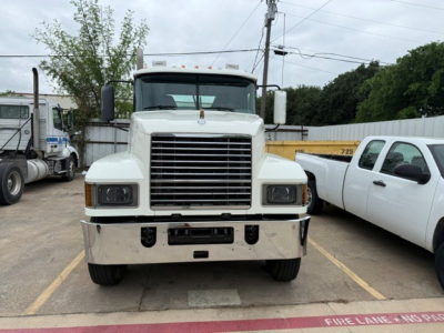Front view of a white 2019 Mack PI64T conventional daycab truck in a parking lot showing large chrome grille, bumper, and headlights.