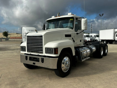 Mack PI64T conventional daycab truck in white, front-left view showing large grille, dual rear axles, fuel tanks, and side mirrors.