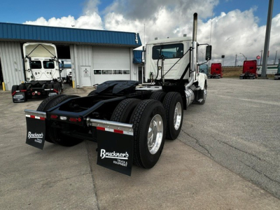 Tractor unit rear view of a white 2019 Mack PI64T conventional daycab showing dual rear axles and fifth wheel with Bruckner's mud flaps.