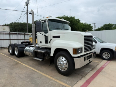 Truck cab and chassis showing Mack PI64T with white exterior and tall exhaust stacks.