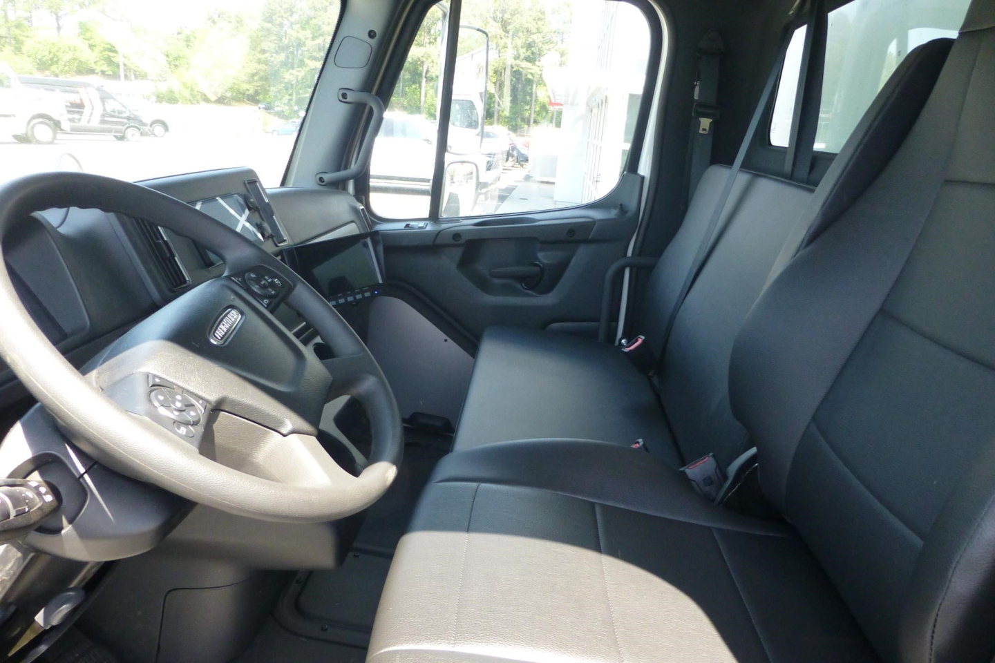 Truck cab interior showing steering wheel, dashboard, and front seats of a Freightliner M2 106.