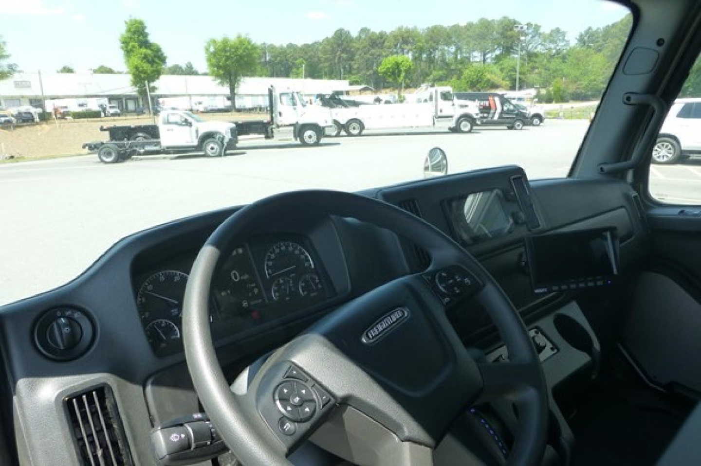Freightliner M2 106 truck interior view showing steering wheel, gauge cluster, and dashboard displays.