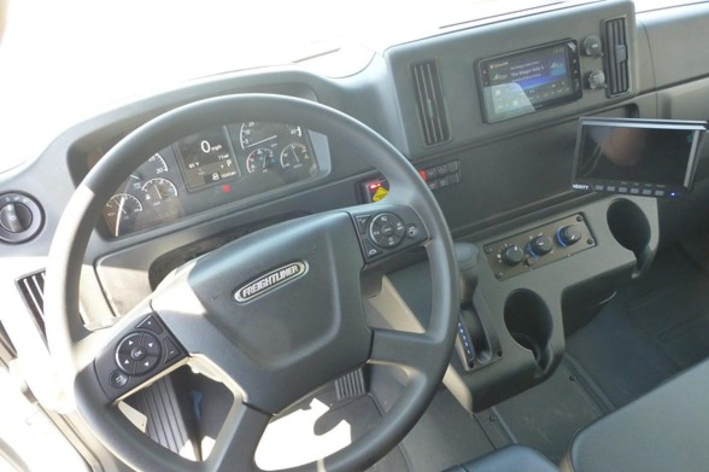 Freightliner M2 106 interior view showing steering wheel, instrument cluster, dashboard touchscreen, and center console