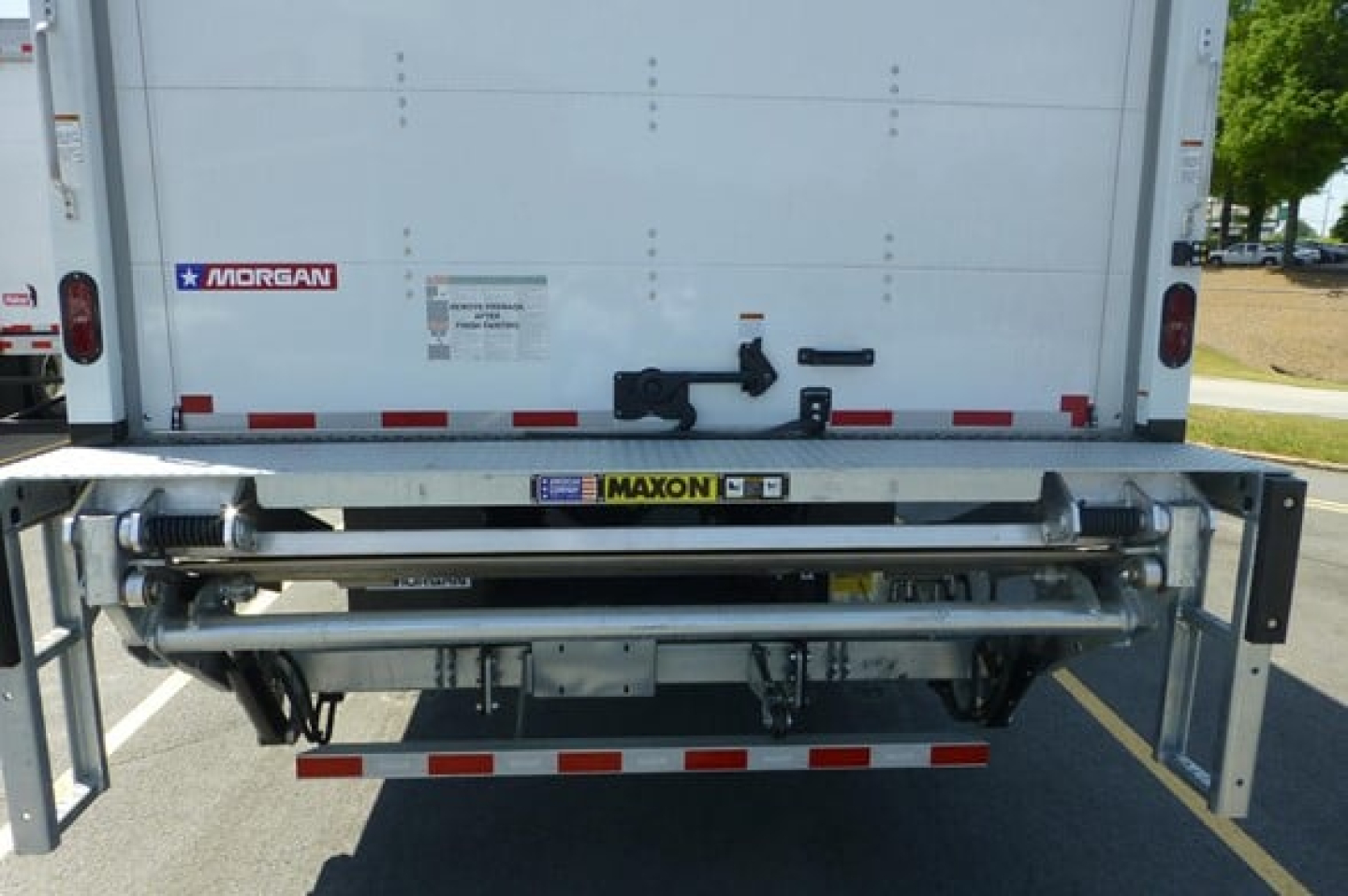 Rear view of a Freightliner M2-106 truck with Maxon liftgate and Morgan body hardware visible, showing rear bumper, lights, and mounting hardware.