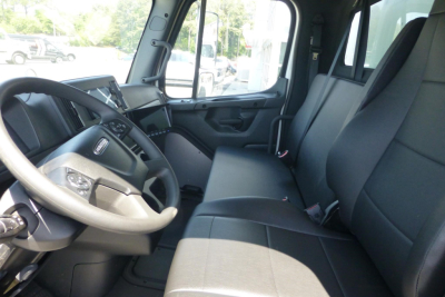 Truck cab interior showing steering wheel, dashboard, and front seats of a Freightliner M2 106.