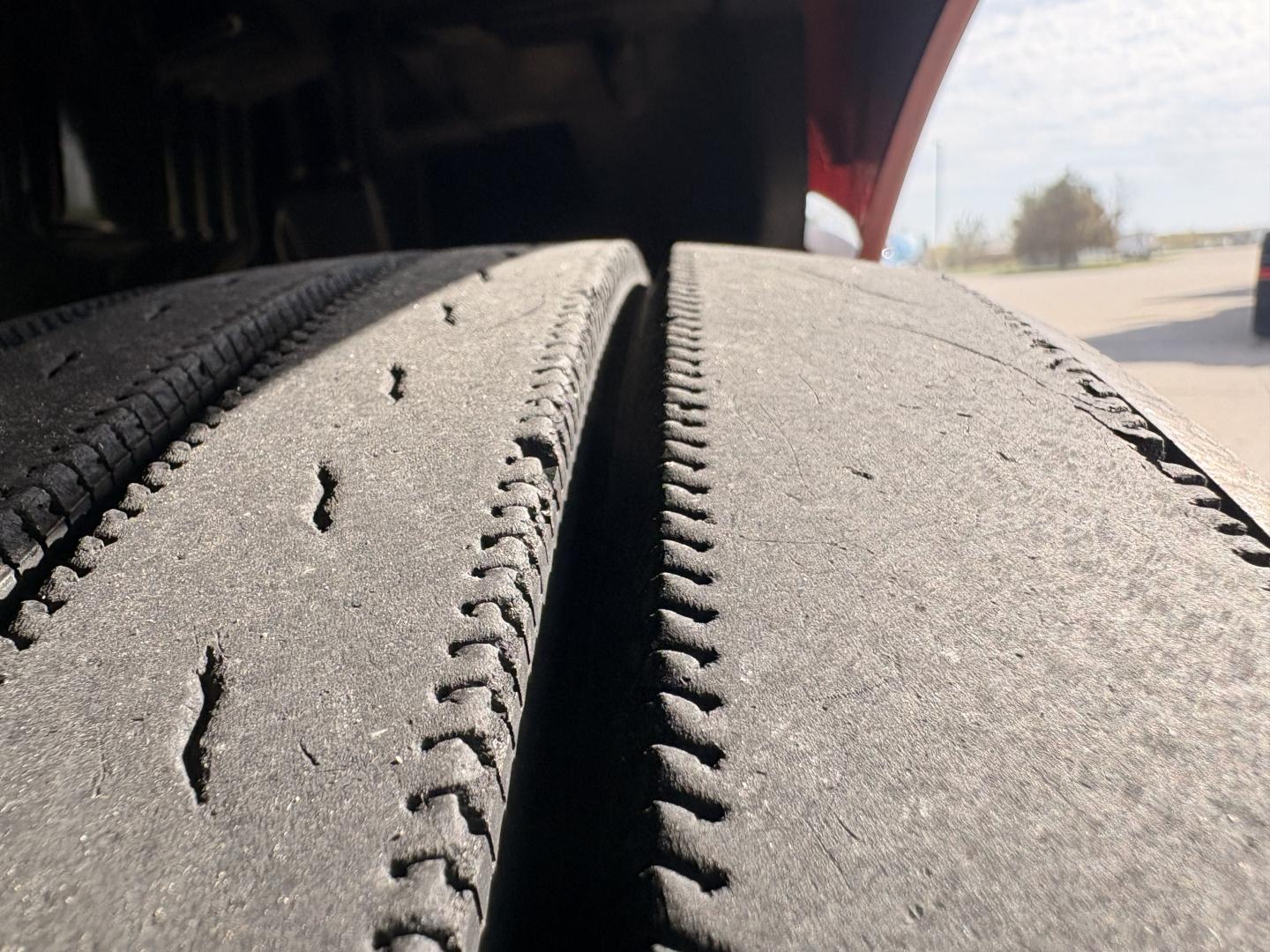 Truck tire tread close-up on Kenworth T680 wheel well area showing dual rear tires and road grime.