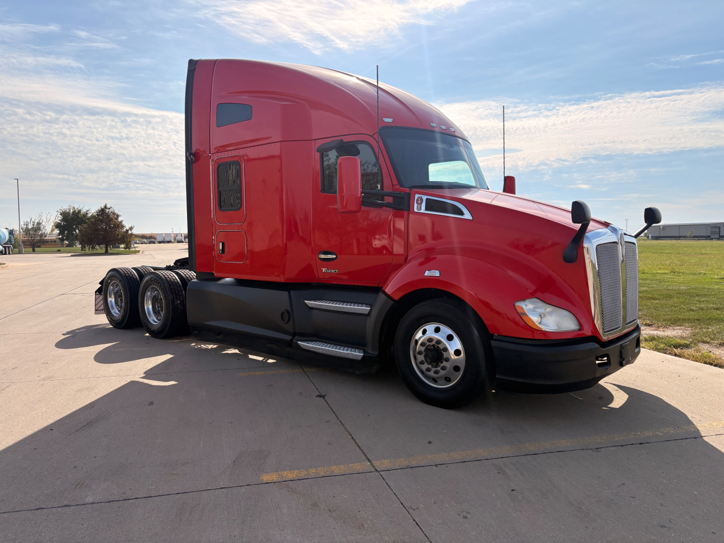 Kenworth T680 tractor-trailer in red, side view showing sleeper cab and front grille with dual rear axles and wheel covers.