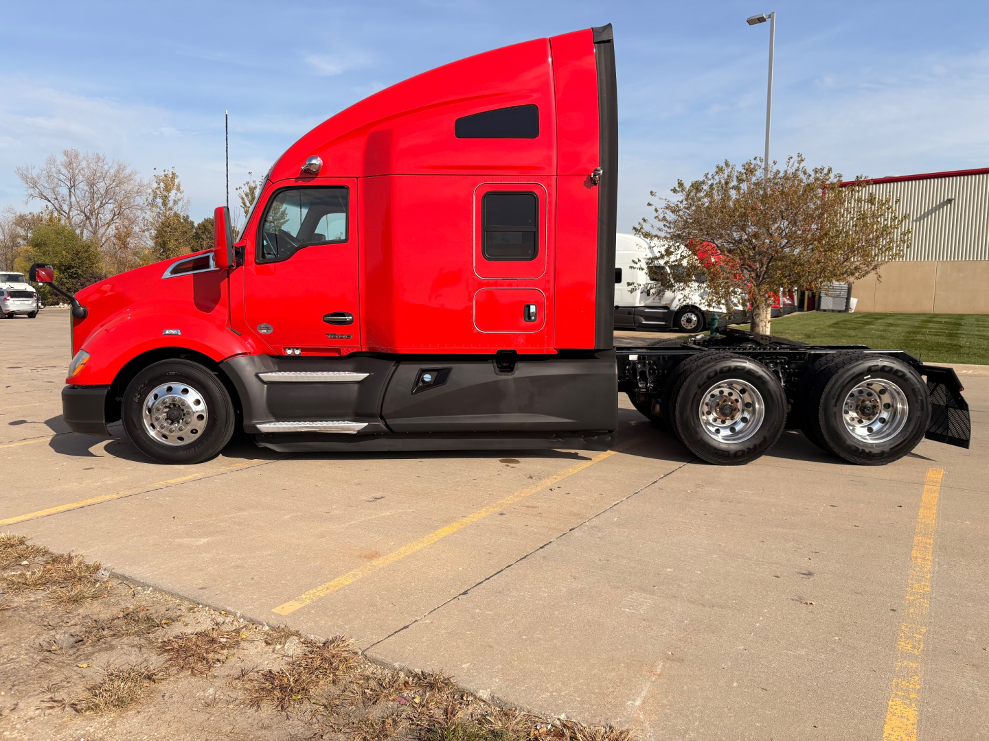 Kenworth T680 red highway tractor side view showing cab with sleeper, rear wheels, and chassis