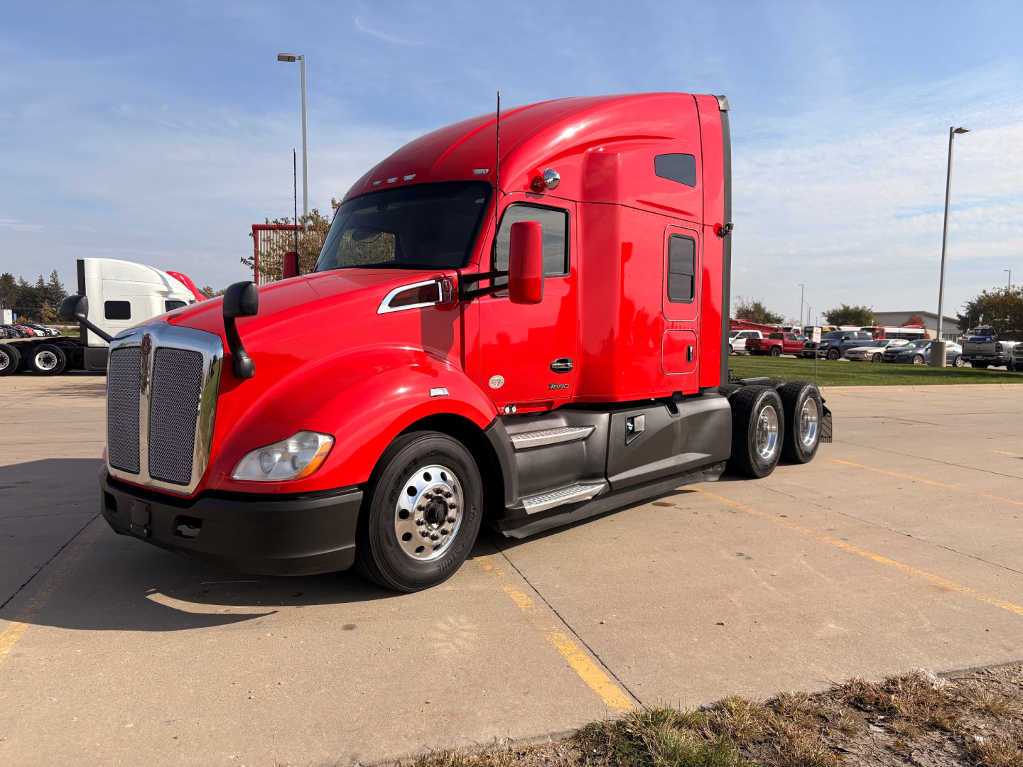 Kenworth T680 sleeper cab truck in red, front three-quarter view with large chrome grille, dual front wheels, and aerodynamic mirrors.