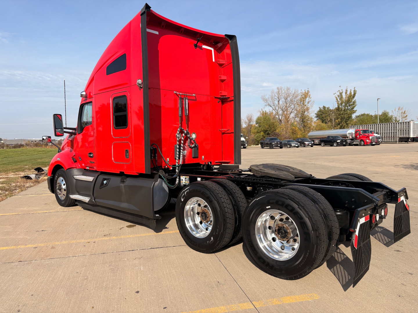 Kenworth T680 tractor rear/side view showing red cab, dual rear axles, chrome wheels, and mud flaps.