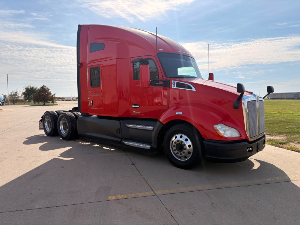 Kenworth T680 tractor-trailer in red, side view showing sleeper cab and front grille with dual rear axles and wheel covers.