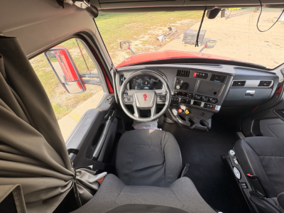 Kenworth T680 cab interior showing steering wheel dashboard controls and driver's seat.