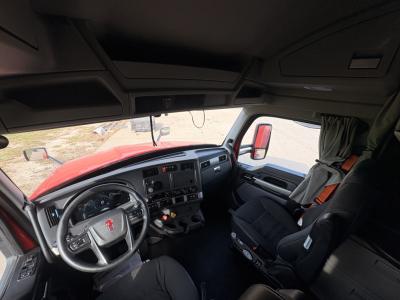 Kenworth T680 truck cab interior showing steering wheel, dashboard, and driver seat with control panels and window controls.