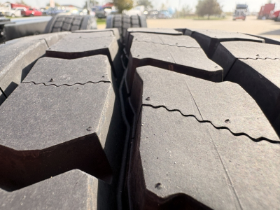 Close-up view of large truck tires/tracks on a Kenworth T680 showing tread blocks and surface details.