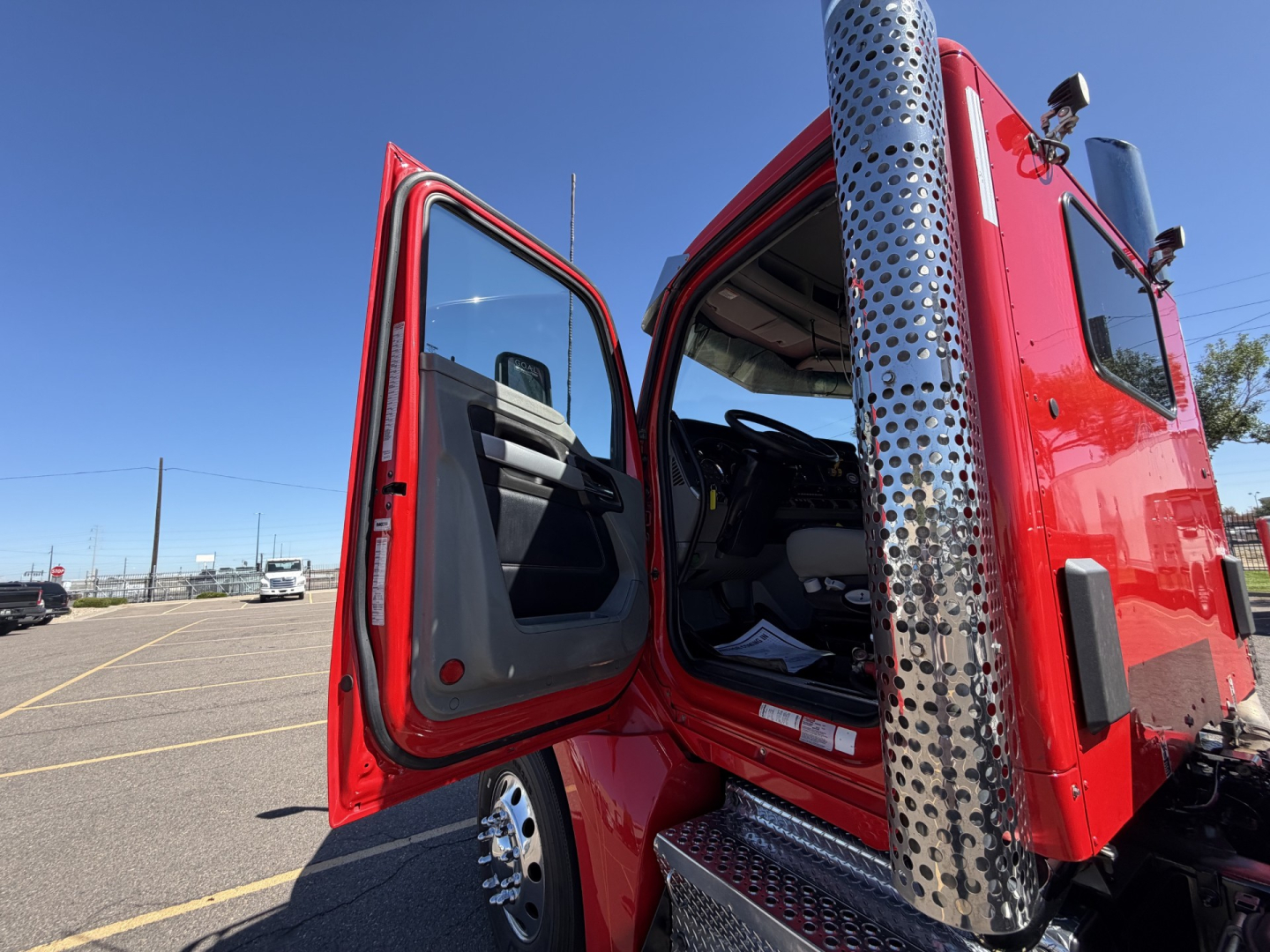 Kenworth T880 cab interior and door area with red exterior, chrome exhaust stack, and open door showing the driver seat and cabin.