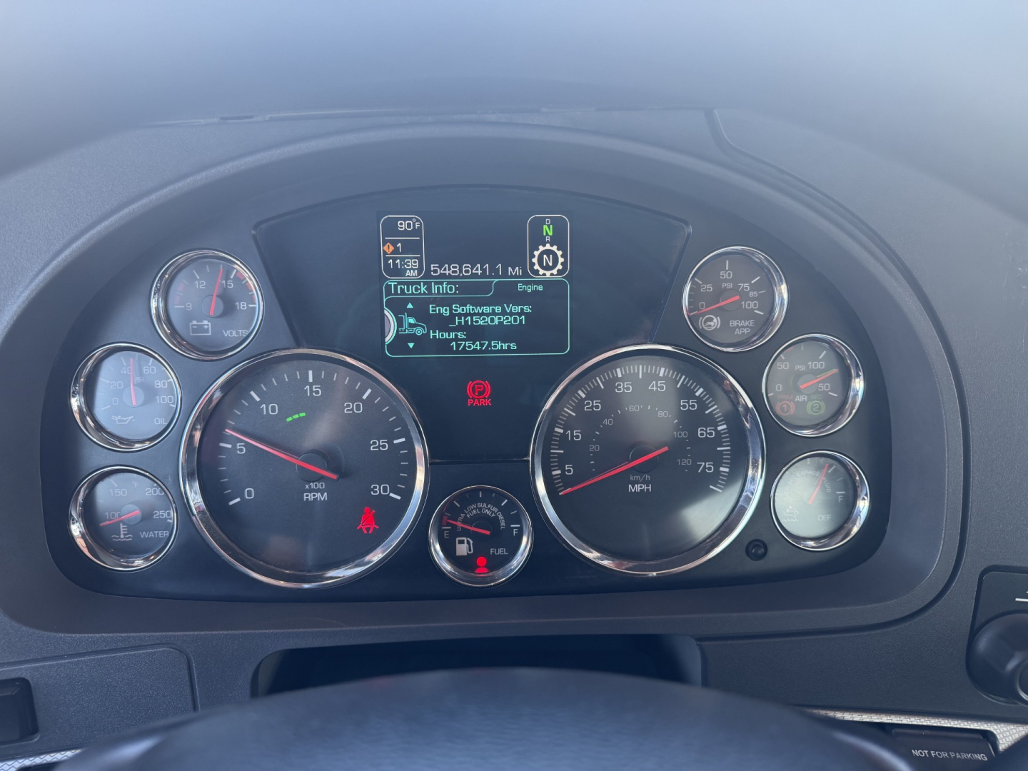 Kenworth T880 instrument cluster dashboard with multiple gauges and digital display showing engine, truck info, and odometer in center.