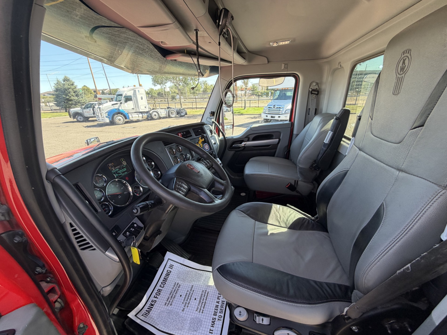 Kenworth T880 interior cabin showing steering wheel, dashboard, and front seats with light gray upholstery.