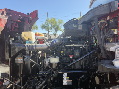 Kenworth T880 engine bay showing air intake, coolant reservoir, and various hoses and wiring.
