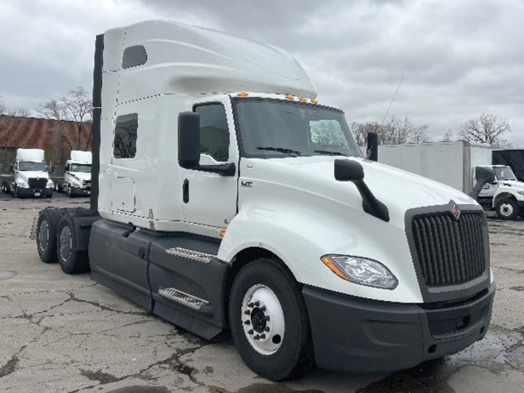 Truck cab side view showing International LT625 sleeper tractor with white exterior, black bumper, large grille, and dual rear axles. No visible text on components.