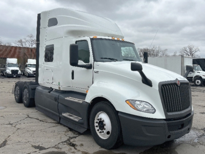 Truck cab side view showing International LT625 sleeper tractor with white exterior, black bumper, large grille, and dual rear axles. No visible text on components.