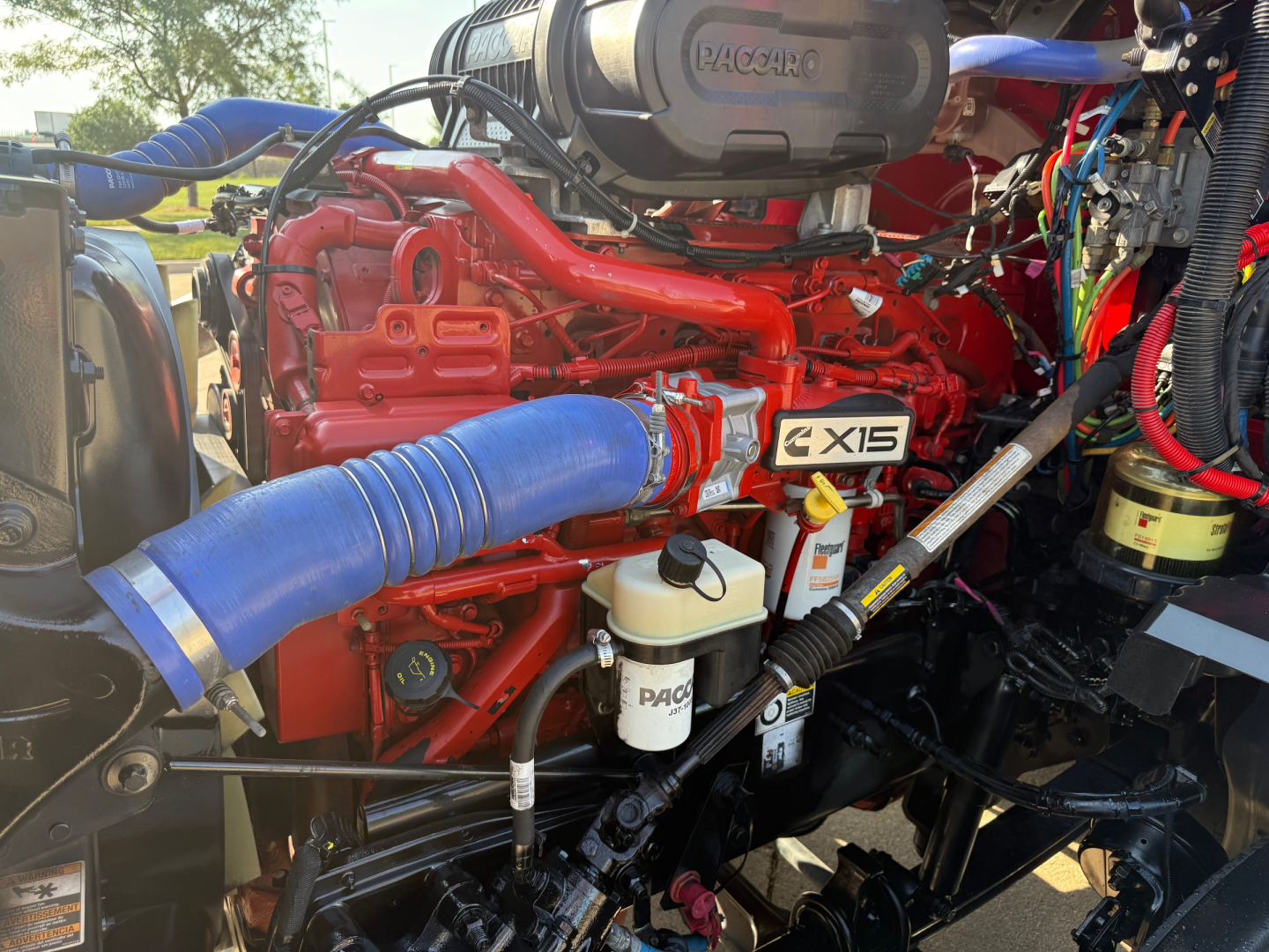 Kenworth T680 engine bay showing X15 label and blue intercooler hose.