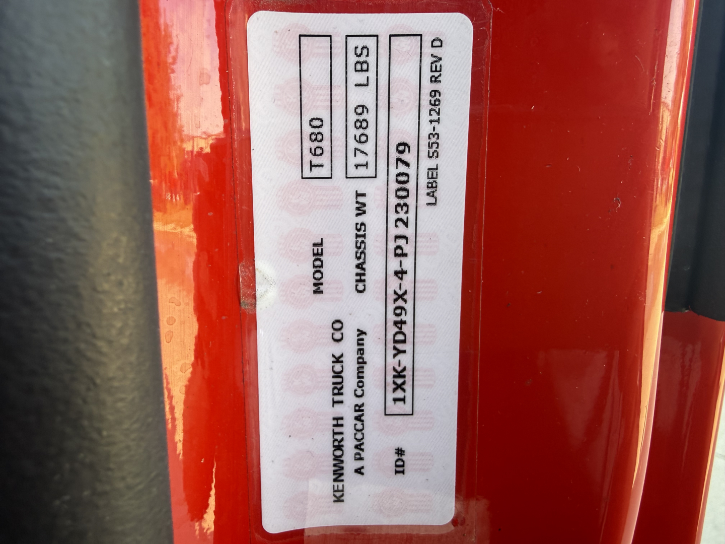 Label on Kenworth truck showing model T680, weight 17689 lbs, VIN 1XKYD49X4PJ230079, stock 0630803, tag with miscellaneous codes.
