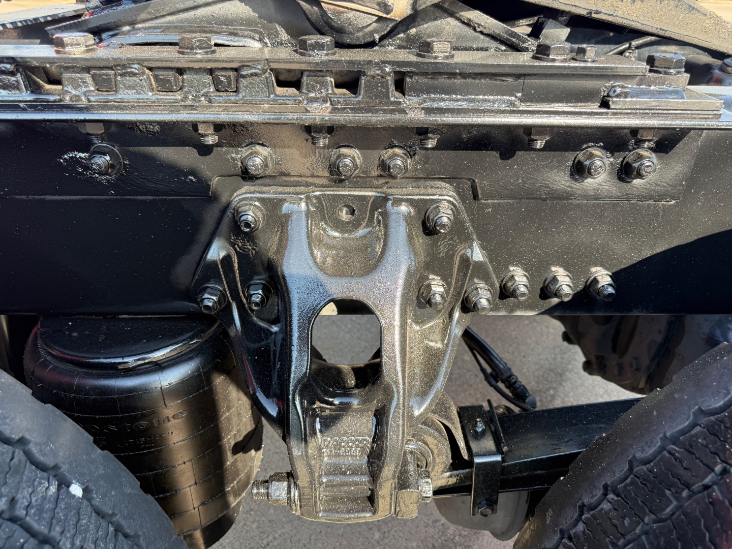 Truck rear view undercarriage showing suspension hitch assembly and air reservoir on Kenworth T680.