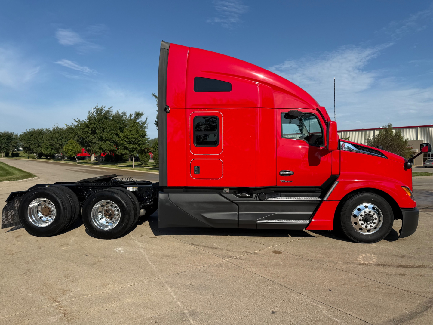 Kenworth T680 sleeper cab truck side view showing red exterior and dual rear axles