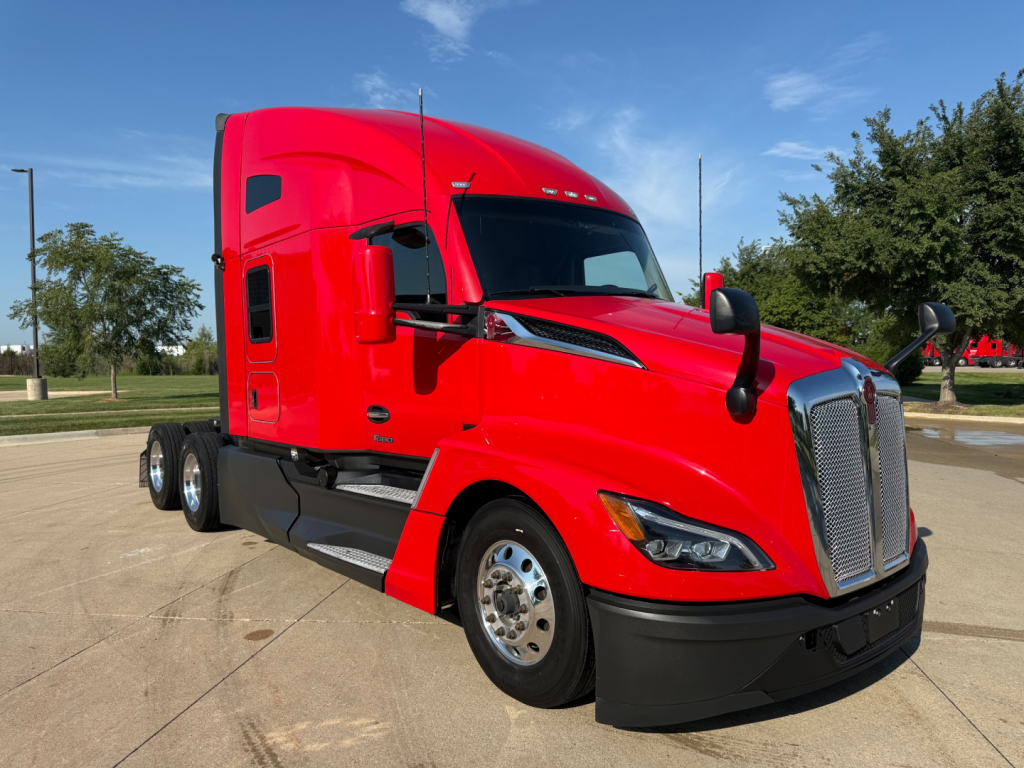 Kenworth T680 tractor in red, side view showing cab, grille, chrome mirrors, front fender, and dual rear wheels.