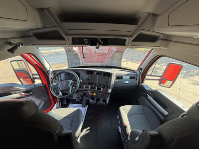 Kenworth T680 truck cockpit interior with steering wheel, dashboard screens, and two front seats visible.
