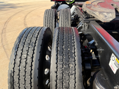 Kenworth T680 tractor axle area showing dual rear wheels and chassis frame with tires and suspension components.