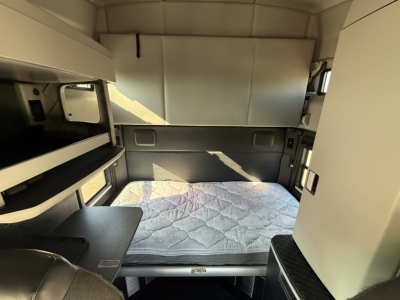 Interior sleeper cab of a Kenworth T680 showing a mounted bed with mattress, side storage, and bunk area.