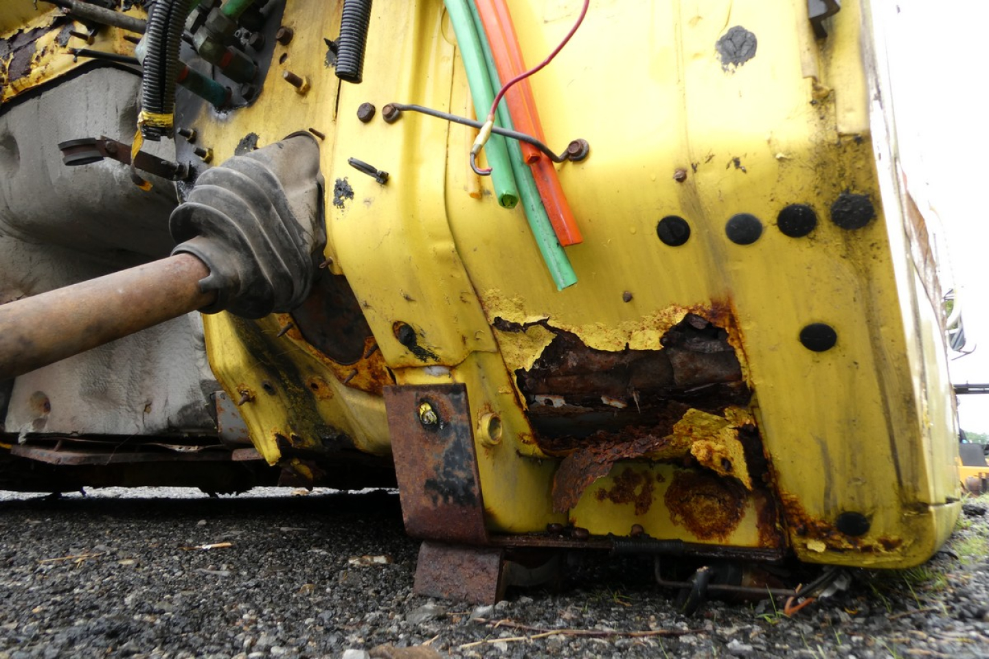 Vehicle cab body showing yellow metal with rust damage near bottom edge and exposed wiring harness of a 1993 International 4700 cab assembly.