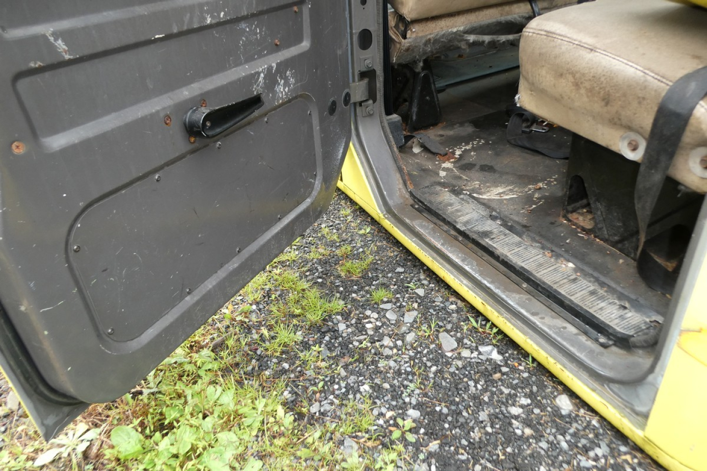 cab interior and door sill of a yellow 1993 International 4700 quad cab showing front passenger seat, floor area, and door opening.