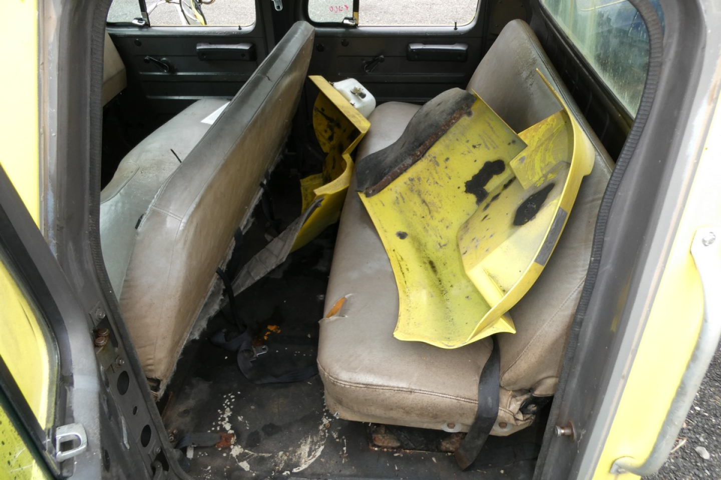 Interior of a 1993 International 4700 quad cab showing torn yellow plastic seat backs and worn seats.