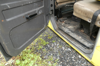 cab interior and door sill of a yellow 1993 International 4700 quad cab showing front passenger seat, floor area, and door opening.