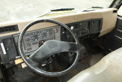 INTERNATIONAL 4700 quad cab truck interior showing steering wheel, dashboard with gauges, and worn brown seats.