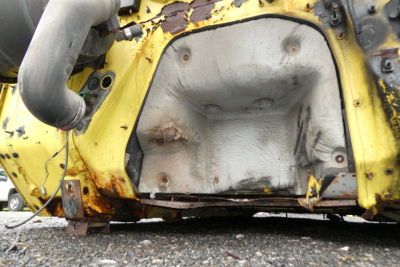 Truck cabin floor pan and underbody of a yellow International 4700 quad cab showing corrosion and rust-free metal, exposed interior structure and side frame.