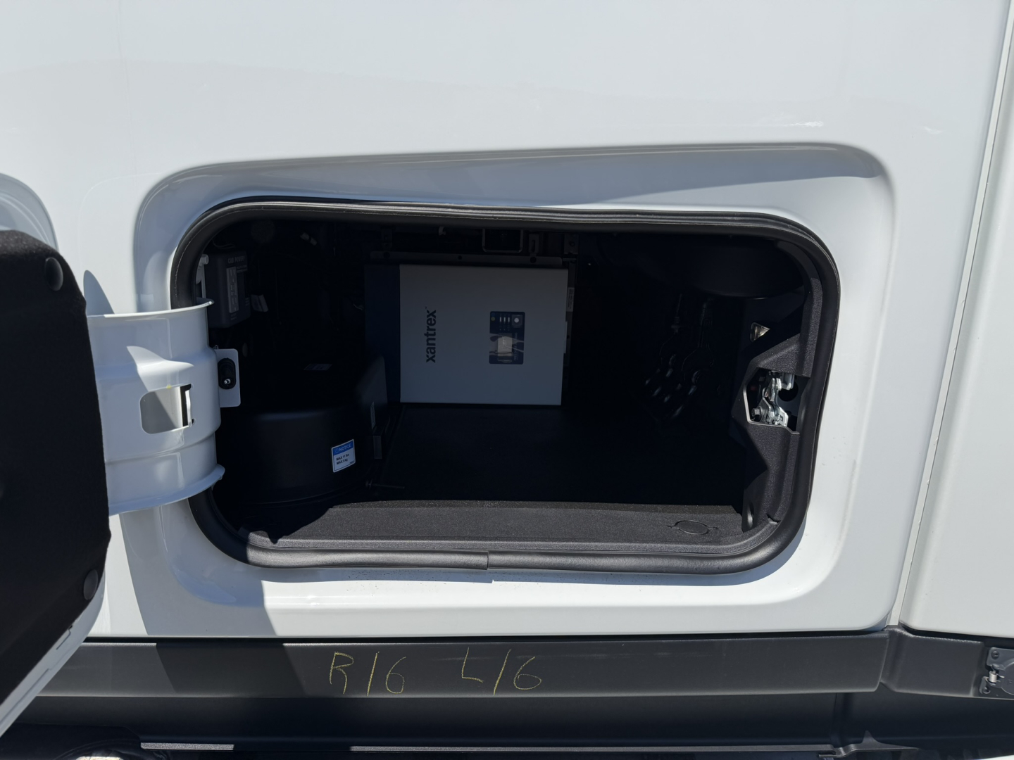 Truck cab storage compartment showing a white Mack box inside the front storage bay of a 2027 Mack PR64T76H day cab.