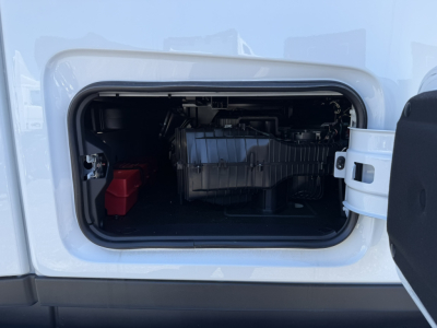 Truck side cab door opening showing engine compartment in front cab with battery and components.