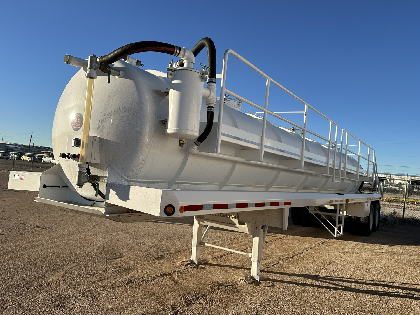 Dragon 130BBL trailer showing cylindrical tank and dual rear axle with ladder and railing, white painted with hoses and fittings.